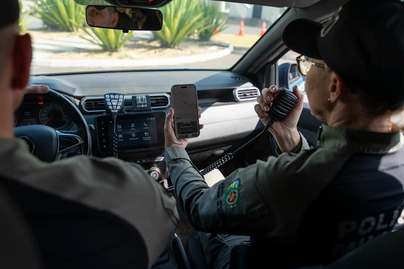Policiais militares de Goiás dentro de viatura usando rádio e celular no apoio às ocorrências do programa IA Contra o Crime