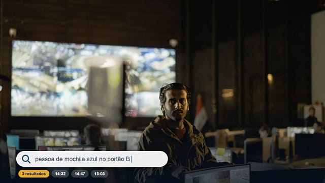 Operador em central de monitoramento com videowall de câmeras e barra de busca de imagens por texto, tema da Intelbras no SegSummit 2026